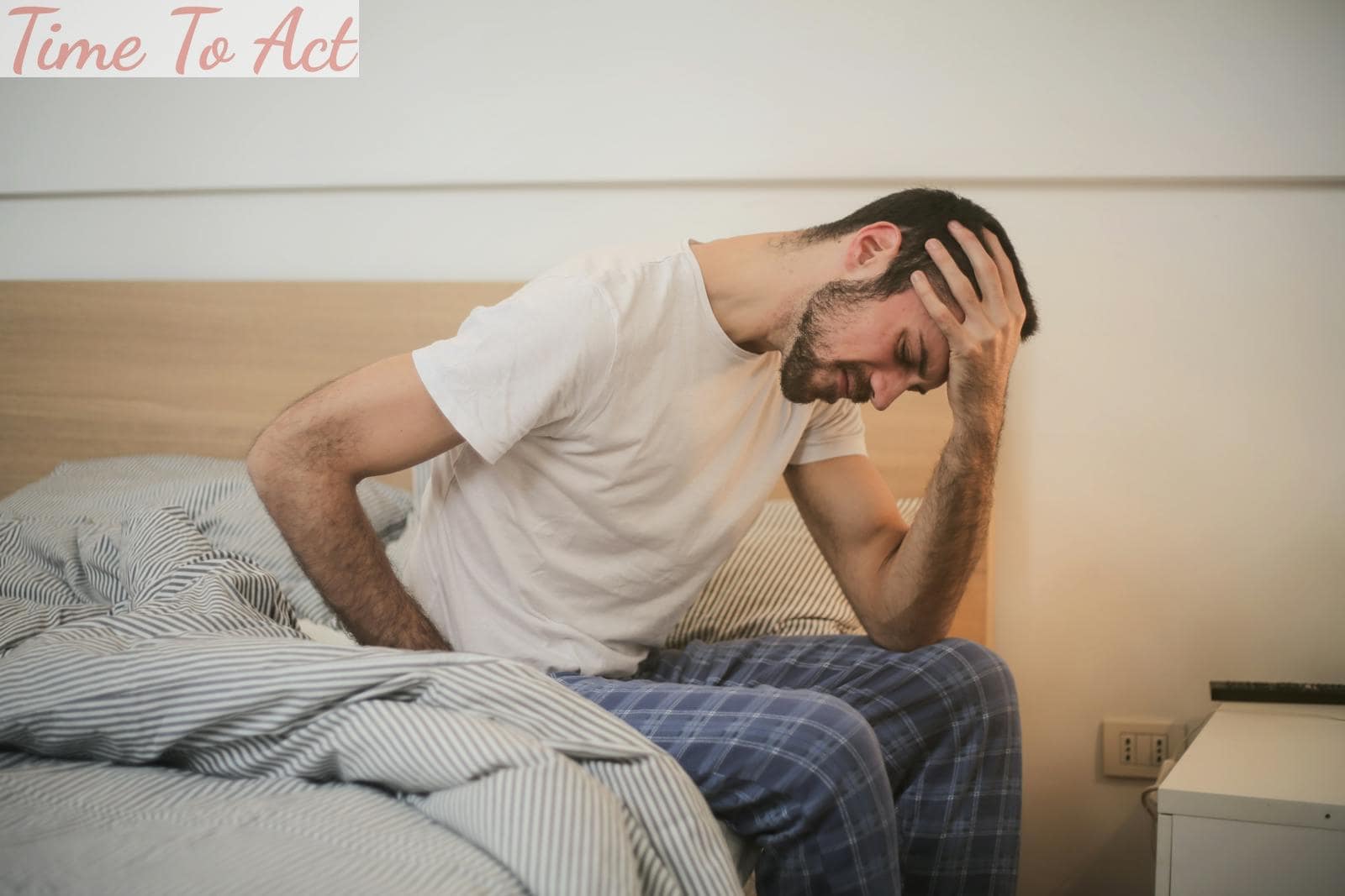 Young man in sleepwear suffering from headache in morning
