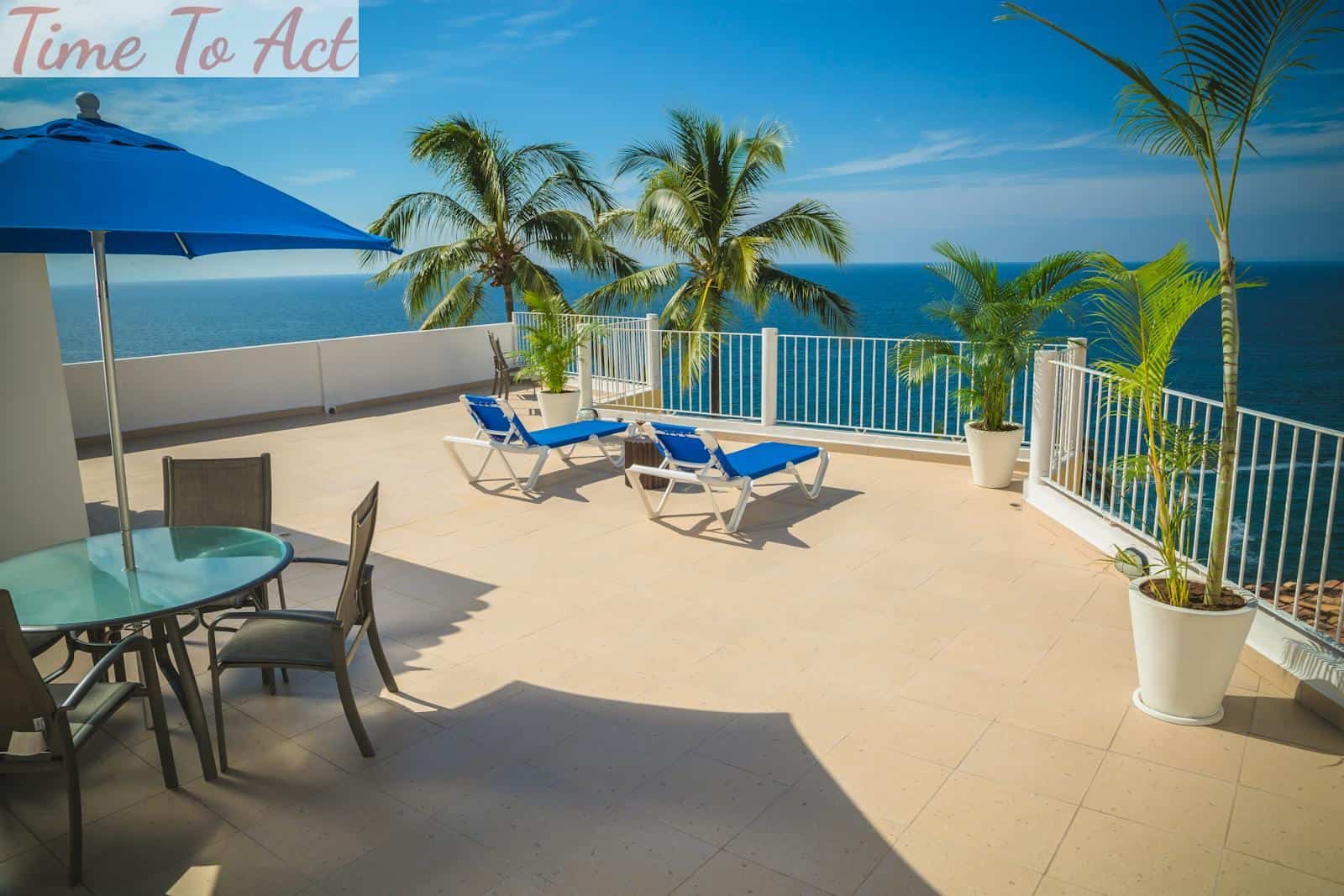 Relaxing beachfront terrace with lounge chairs and ocean view under blue skies.